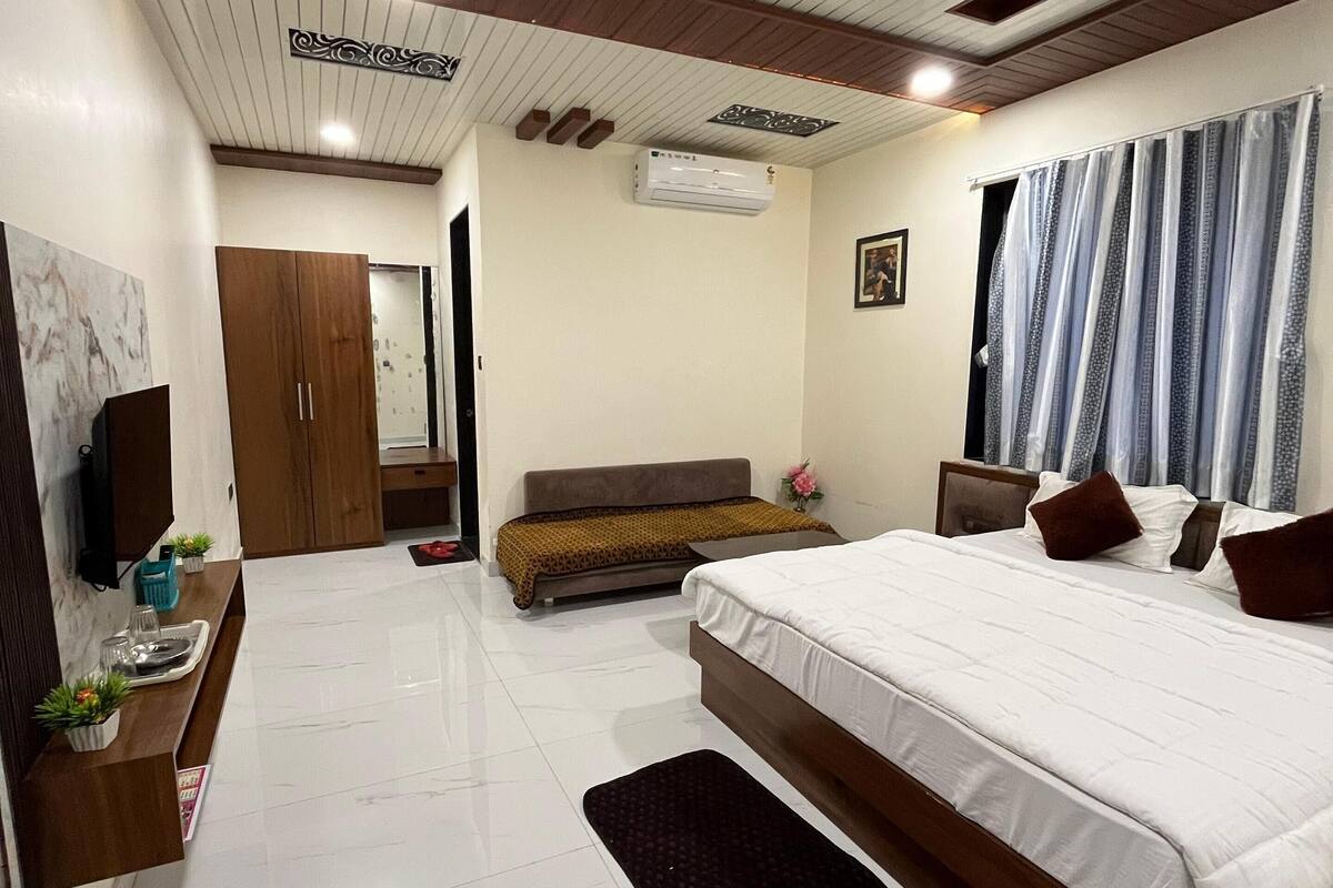 A modern bedroom with a large bed, a bedside table, a TV, and a wardrobe.