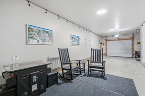 A garage with two chairs, a desk, and two framed pictures on the wall.