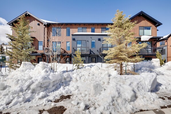 Un bâtiment moderne à plusieurs étages, doté de grandes fenêtres et d’une façade combinant des éléments en bois et en métal.