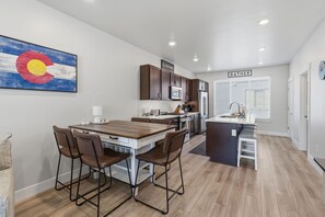 A modern kitchen with dark wooden cabinets, a central island, and a dining area with four chairs.