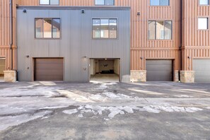 A building with two garage doors, a concrete driveway, and a stone pillar.