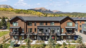 A modern two-story building with a balcony and a view of mountains.