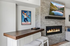 A modern living room with a fireplace, a mounted TV, and a poster on the wall.
