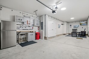 A spacious, well-lit kitchen with stainless steel appliances, a pegboard with tools, and a red trash bin.