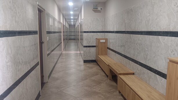 A hallway with marble walls, wooden benches, and a ceiling with recessed lighting.