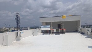 A rooftop with a water tank, air conditioning units, and a ladder.