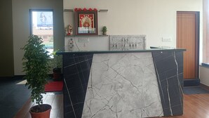A reception desk with a marble design, a framed picture above it, and a potted plant to the left.