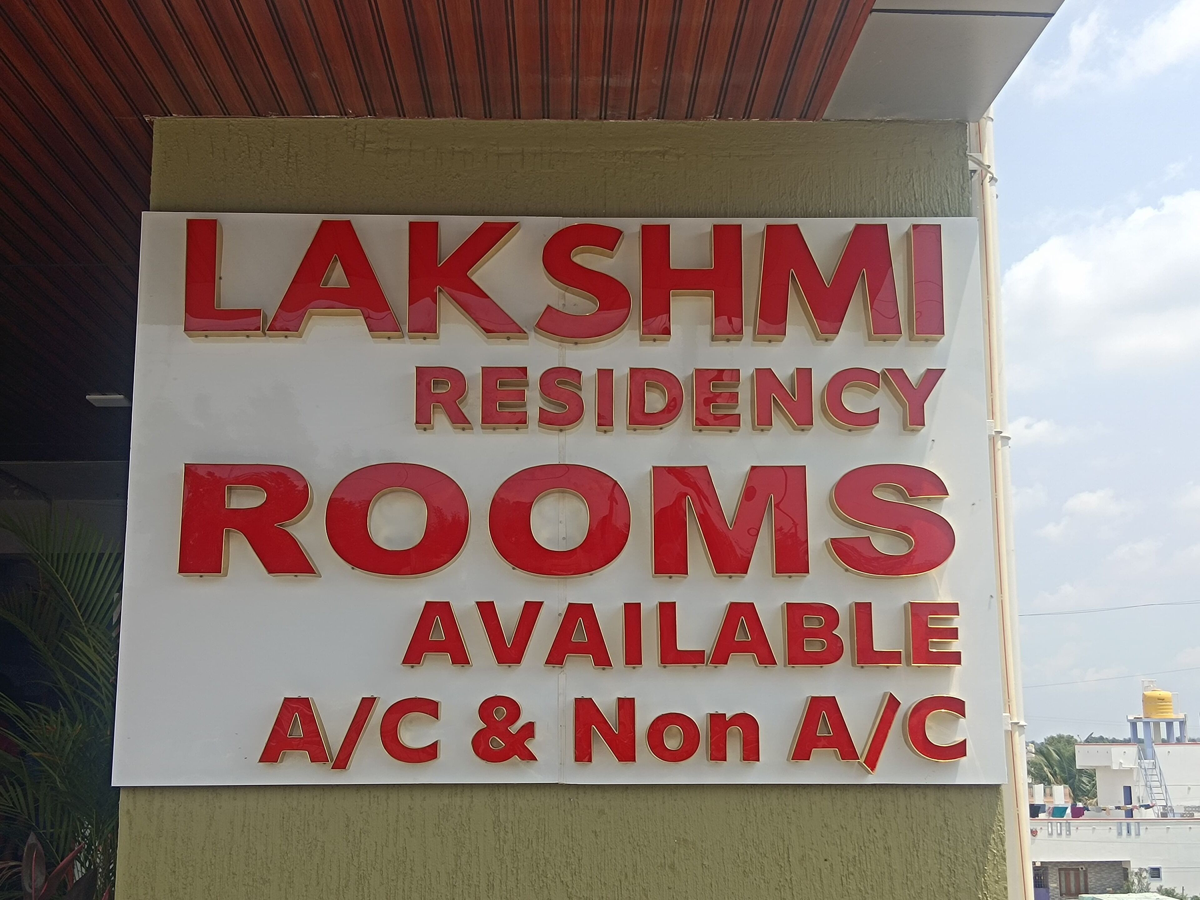 A sign for Lakshmi Residency Rooms available for A/C and Non A/C.