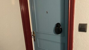 Una puerta azul con una placa de número, un timbre y un felpudo con la inscripción 'hogar dulce hogar'.