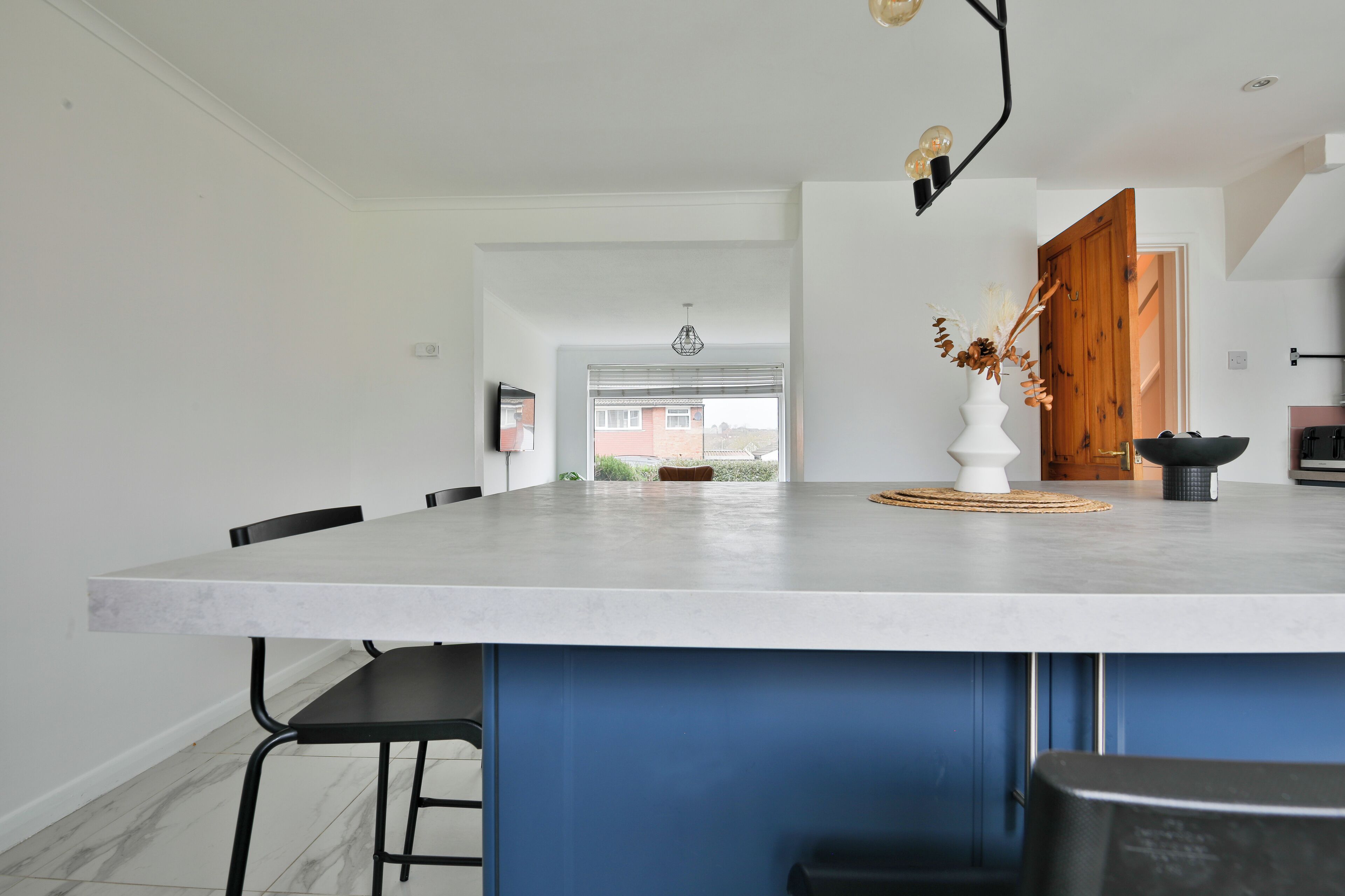 A modern kitchen with a large island, white walls, and blue cabinetry.