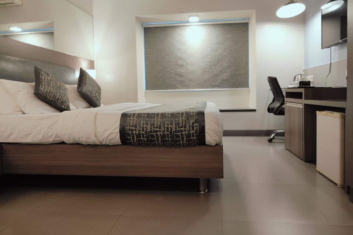 A modern hotel room with a bed, a desk, and a window.