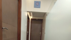 A hallway with a 'No Smoking' sign, a door with a number, and a staircase. - Apollo Guest House – Colaba Causeway (Mumbai)