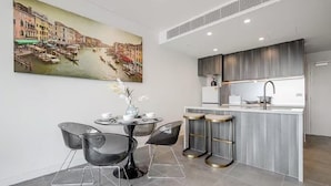 Una cocina moderna con una isla central, taburetes de bar y una zona de comedor con mesa y sillas.