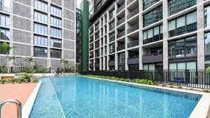 Un edificio moderno con piscina, balcones y fachadas de vidrio y ladrillo.