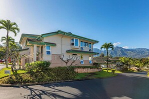 A two-story house with a green roof, a balcony, and a view of mountains in the background. - Villas Of Kamalii 55: 3 BR, 3 BA Condominium in Princeville, Sleeps 6 (Princeville)