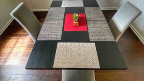 Une table à manger avec un plateau rouge, entourée de quatre chaises, posée sur un tapis à motifs.