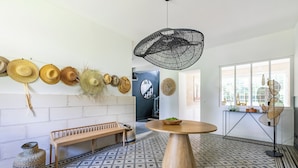 A modern interior with a patterned floor, a wooden bench, a round table with a bowl, and a hanging light fixture.