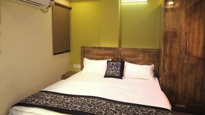 A neatly made bed with a patterned throw, a wooden headboard, and a wardrobe with a mirror. - Casa Central (New Delhi)
