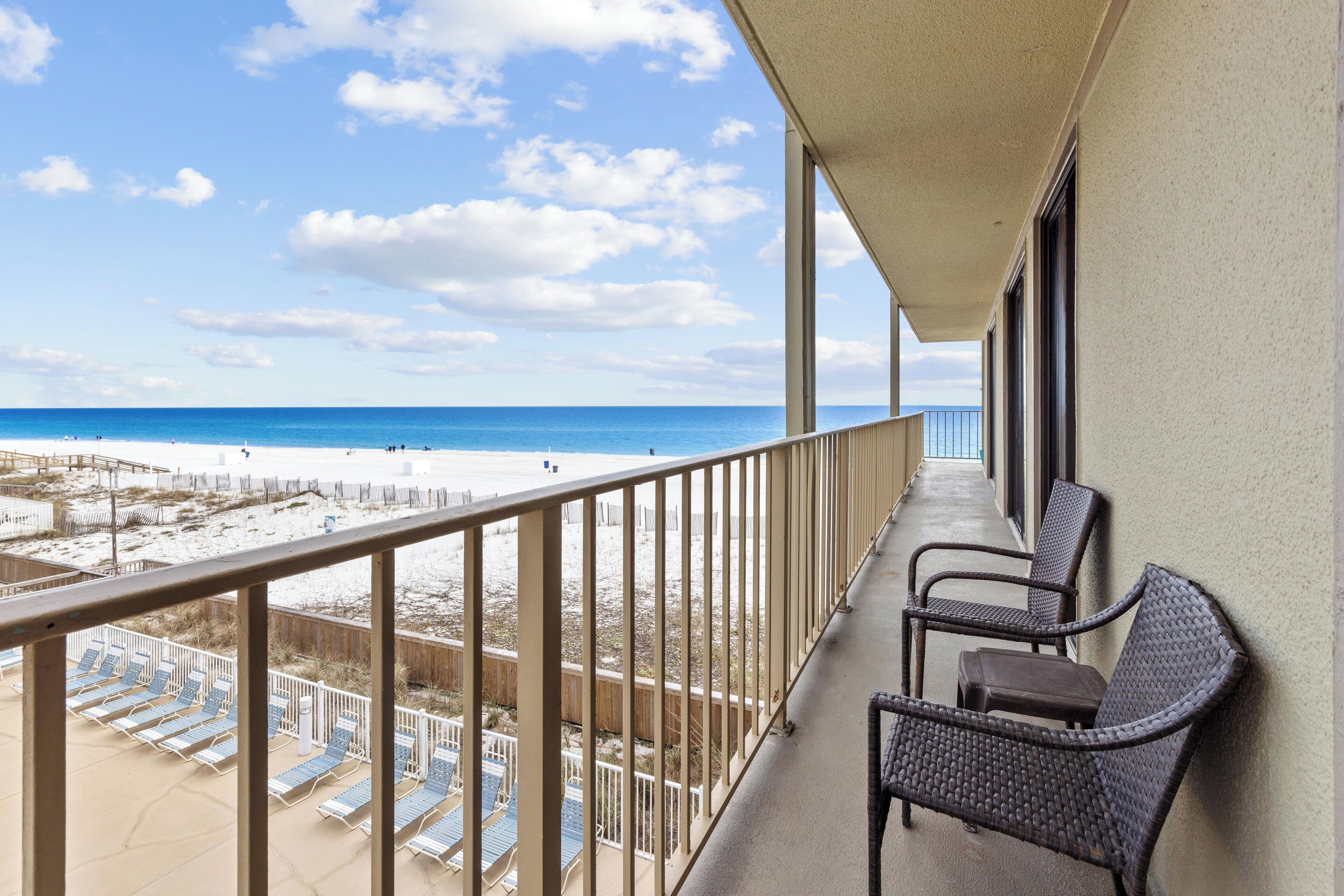 A balcony with a view of the beach and ocean.