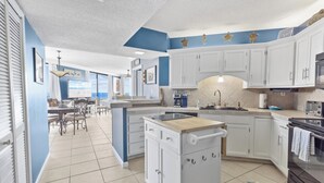 Une cuisine moderne avec des meubles blancs, un îlot central et un coin repas comprenant une table et des chaises.