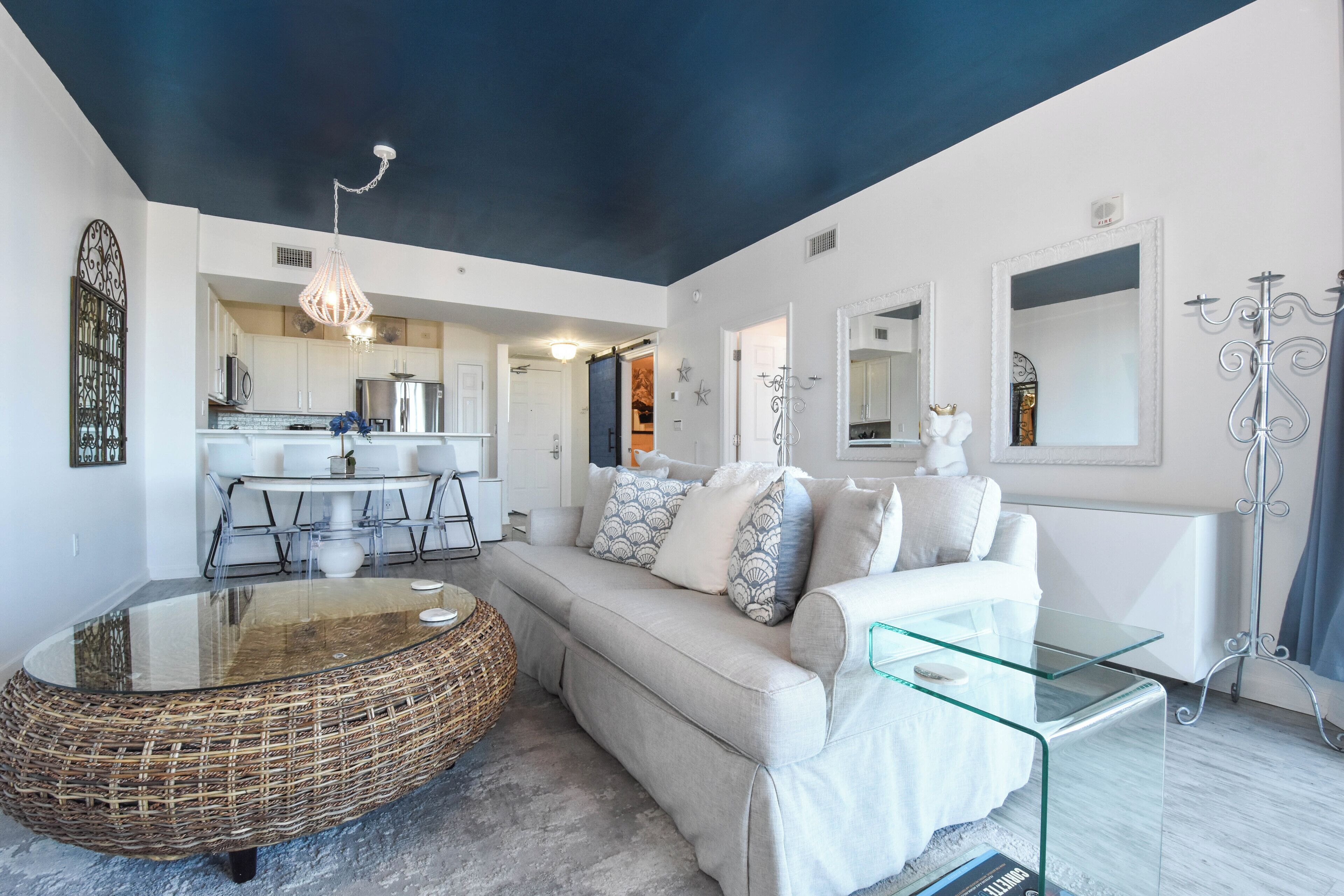 A modern living room with a sofa, glass coffee table, and a wicker ottoman.