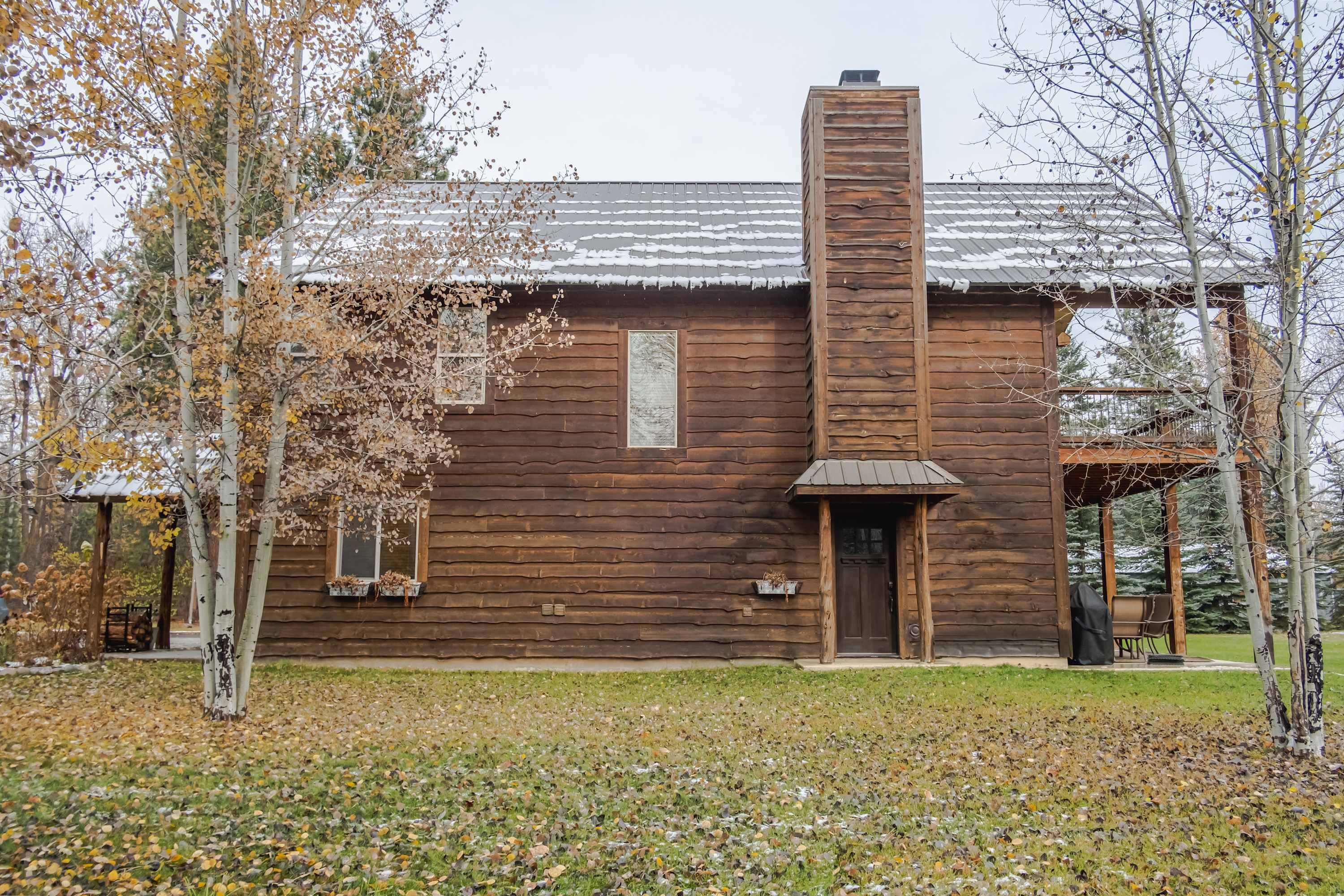 A rustic wooden cabin with a chimney, a porch, and a small garden area.