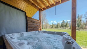 A hot tub with a wooden deck and a view of a mountainous landscape. - Flathead River Retreat For 15! (Columbia Falls)