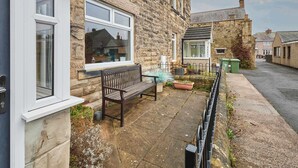 A stone house with a bench outside, a window, and a small garden area. - Host & Stay | Hope Terrace (Amble)