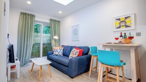 A modern living room with a sofa, a small table, and a dining area with chairs. - Host & Stay | Croydon Road Abode (Caterham)