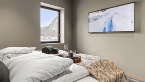 A bedroom with a bed, a window, a framed picture, and a bedside table with a candle. - Penthouse with amazing fjord view (Vestland)