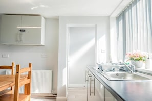 Una cocina moderna con una mesa de comedor de madera, armarios blancos y un ventanal con cortinas.