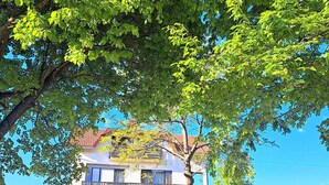 A two-story building with a balcony, surrounded by trees and a clear sky. - Apartments Villa Mavi (Rakovica)