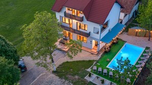 Een modern huis met twee verdiepingen, een zwembad, terras en een verzorgd gazon.