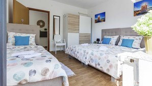 Een slaapkamer met twee bedden, een houten vloer, een witte stoel en een schilderij aan de muur.