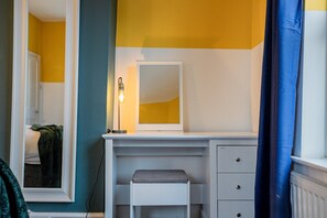 A bathroom with a white vanity, a mirror, and a bench.