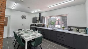 Een moderne keuken met een eethoek, met een bakstenen muur, een klok en een raam met uitzicht op gebouwen.