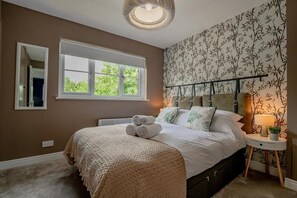 Une chambre avec un grand lit, une fenêtre, un miroir et un mur orné d’un motif en bambou.