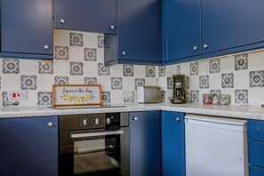 Et køkken med blå skabe, en hvid bordplade og tapetserede backsplash-fliser.
