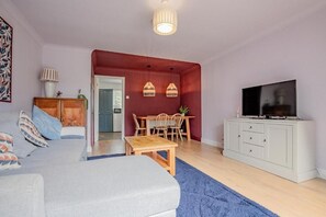Un salon comprenant un canapé, une table basse, un téléviseur et un coin repas avec des chaises et une table.