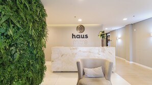 A reception area with a green vertical garden, a marble reception desk, and a plush armchair.