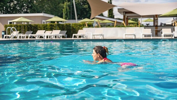 A swimming pool with lounge chairs and umbrellas.