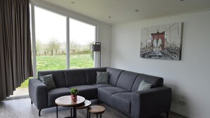 A modern living room with a grey sectional sofa, a small round table, and a painting of a bridge on the wall.