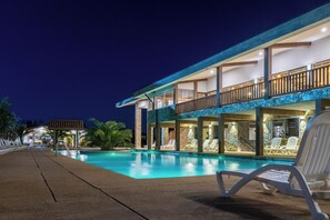A modern hotel with a swimming pool, outdoor seating, and a well-lit balcony area. - Aguas del Monte Hotel & Spa (Tome)