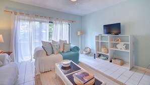 Una sala de estar con sofá, mesa de centro, televisor y estantería.