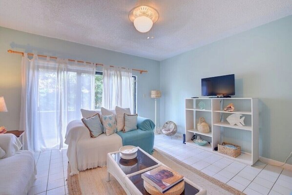 A living room with a sofa, a coffee table, a television, and a bookshelf.