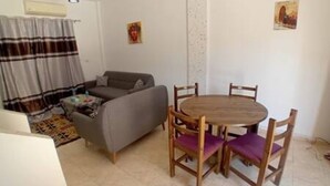 Un salon comprenant un canapé, une table à manger avec quatre chaises et un rideau à motifs.
