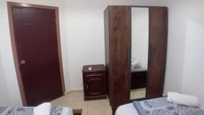 Une pièce comprenant un lit, une armoire, une petite table et une porte.