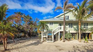 A beachfront property with a two-story house, a covered porch, and a staircase leading to the entrance. - Gulf Front Getaway at Gulf Cottage 1108 (Captiva)