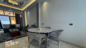 A modern living room with a sofa, a coffee table, and a dining table with chairs. - 129 · 2BR Townhouse, 2 Bath, TV, Backyard (Sheikh Zayed City)