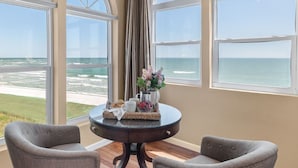 Een kamer met uitzicht op de oceaan, een ronde tafel met een dienblad met snacks, en twee stoelen.